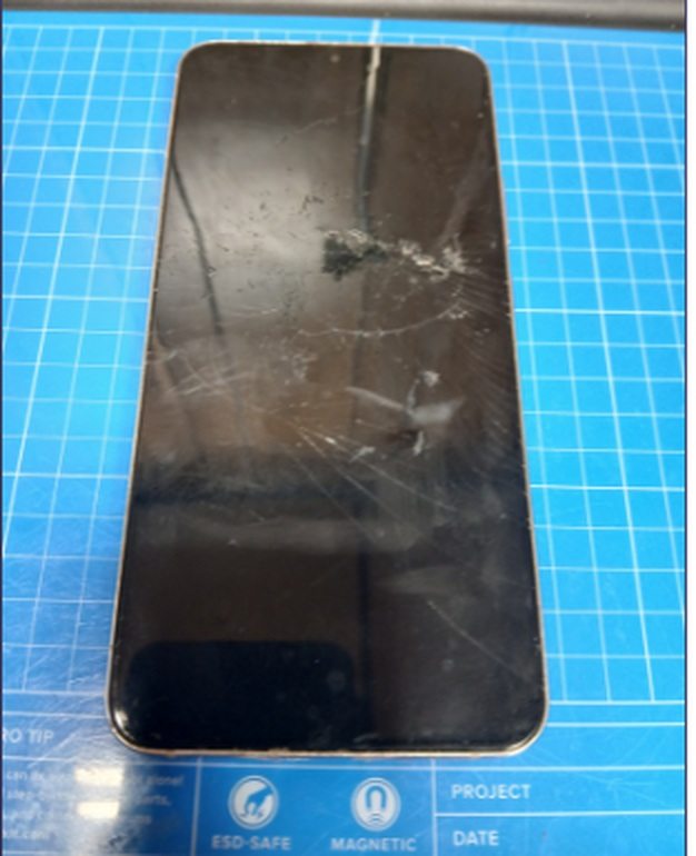 Samsung Galaxy S22 Plus on the bench mat before repair: impact point near the top of the screen with cracks radiating to every edge